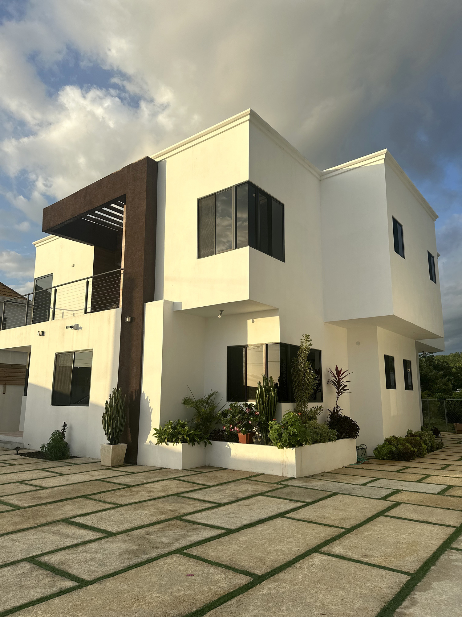 Villa with tropical plants and a stone courtyard in warm evening light